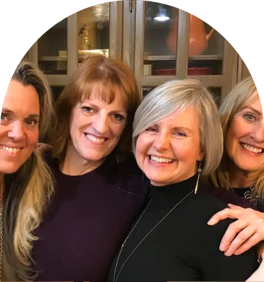 Four women smiling for a picture in front of a green wall.