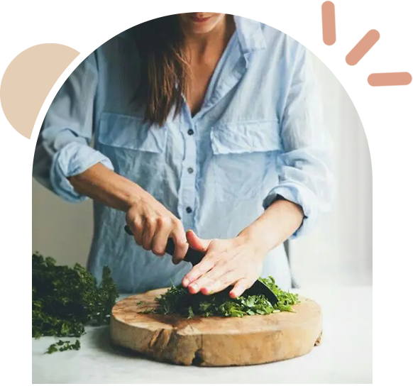 A woman cutting broccoli on top of a wooden board.