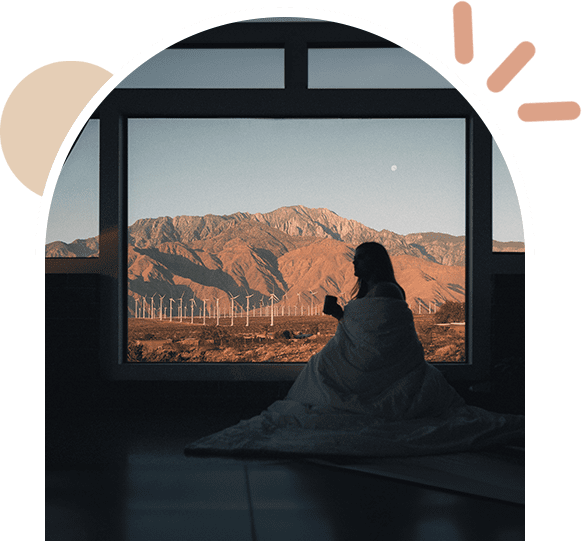 A person sitting in front of a window with mountains