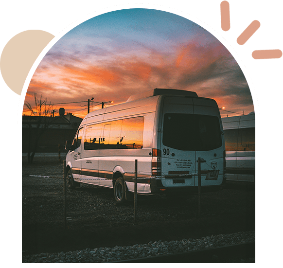 A bus parked in front of the sunset.