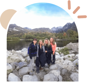 Four women are posing for a picture in front of mountains.